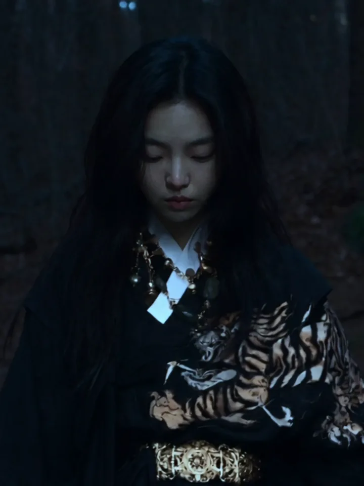 The wraith in a black hanbok, head bowed in the forest